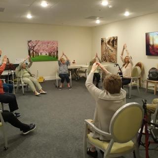 A group of seniors participating in a seated exercise class at a community center.