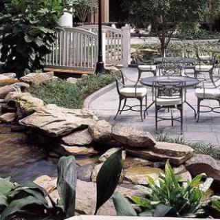 A tranquil garden patio with outdoor seating and a rock-lined water feature.