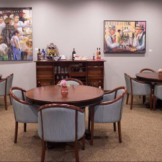 A cozy meeting room with round tables, upholstered chairs, and decorative artwork on the walls.