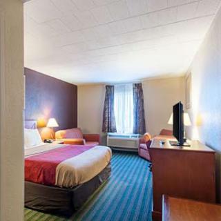A cozy hotel room featuring a queen bed, seating area, and modern amenities.