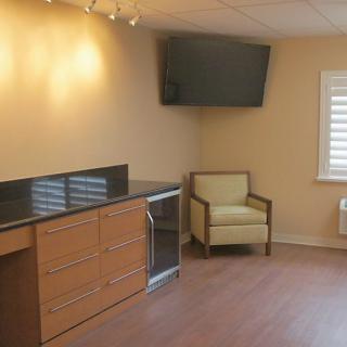 A simple office interior with a chair, cabinet, and wall-mounted television.