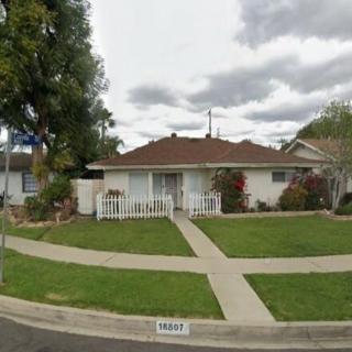 A suburban house with a well-maintained lawn and trees under a cloudy sky.