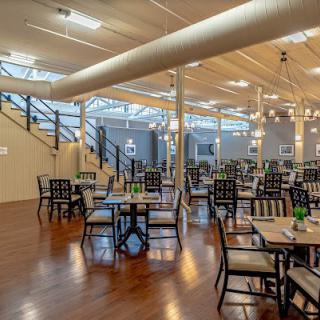 A spacious and modern restaurant interior with neatly arranged tables and chairs, featuring wooden floors and ample natural light.