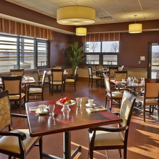 A well-lit dining area with neatly arranged tables and chairs, featuring large windows and stylish interior decor.