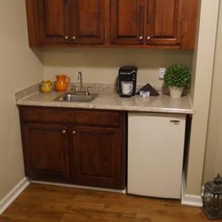A compact kitchenette with a mini fridge, sink, and countertop featuring a coffee maker and decorative items.