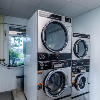 A pair of stacked industrial washing machines and dryers in a laundromat.