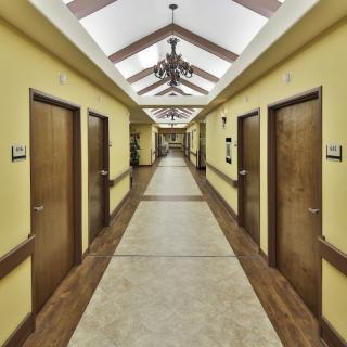 A long, well-lit corridor with multiple doors on each side.