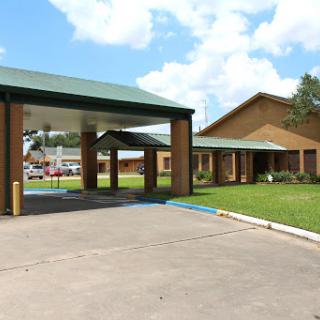 A welcoming entrance to a building surrounded by green grass and a blue sky.