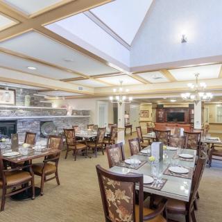 An elegant dining room setup with neatly arranged tables and chairs, featuring warm lighting and sophisticated decor.