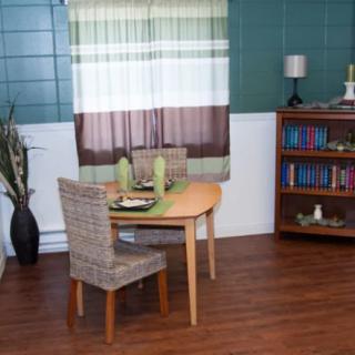 A cozy dining room with a small table, chairs, and a bookshelf.