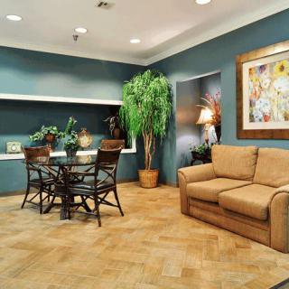 A cozy living area featuring a sofa, dining table, indoor plants, and artwork on the wall.