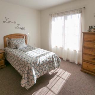 A cozy bedroom with a single bed and sunlight streaming through the window.