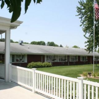 A single-story residential building with a manicured lawn and an American flag flying in the front.