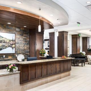 A modern reception area with a wooden desk, decorative flowers, and artwork on the wall.