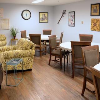 A cozy room with several tables and chairs, adorned with artwork on the walls.
