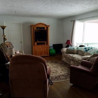 A cozy living room with a sofa, chairs, and a television in an entertainment center.