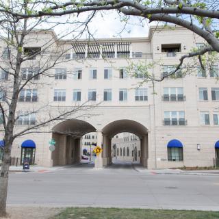 A modern multi-story building with arched entrances and blue awnings.