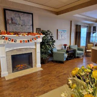 A cozy living room adorned with autumn decorations, featuring a fireplace and comfortable seating.