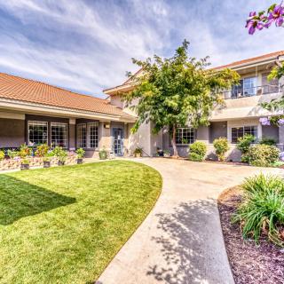 A beautiful two-story house with a well-maintained garden and paved walkway.