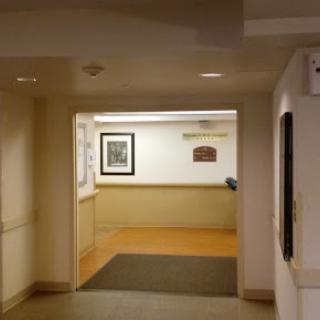 A view of an interior hallway with artwork on the walls and a doorway leading to another space.