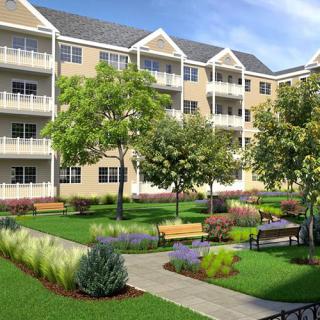 A modern apartment complex with landscaped gardens and a pathway surrounded by lush greenery.