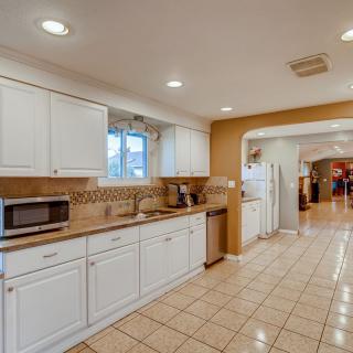 A spacious modern kitchen with white cabinets and tile flooring.