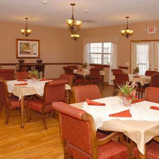 A well-arranged dining room with tables and chairs, adorned with tablecloths and decorative lighting.