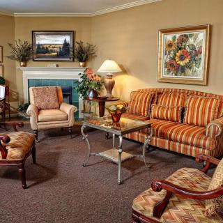 A cozy living room with a striped sofa, armchairs, coffee table, and decorative elements including paintings and lamps.