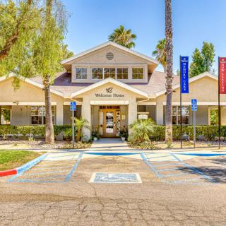 The entrance of a community building with surrounding palm trees and visible parking spaces.