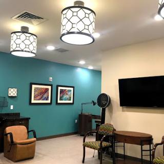 A modern lounge area featuring comfortable seating, decorative lighting, and artwork on the walls.