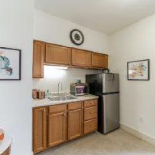A small, compact kitchen with wooden cabinets, a refrigerator, and various appliances.