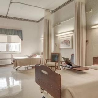 A clean and well-organized hospital room with two beds separated by curtains.