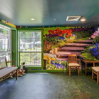 A vibrant indoor space featuring a mural of a garden scene with seating and large windows.