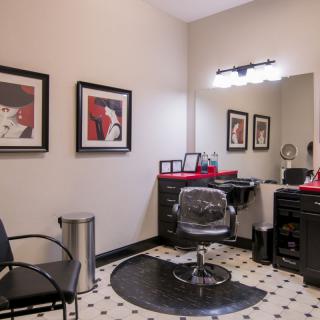 A modern hair salon with stylish decor, featuring a hairdressing station and artwork on the walls.