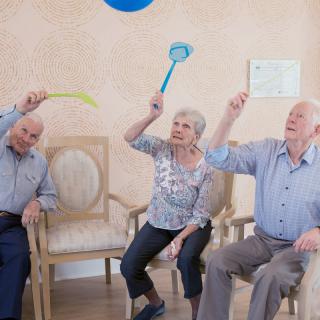 Seniors engaging in a fun indoor activity involving balloons.