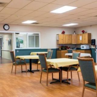 A communal dining area with tables, chairs, and a kitchenette.