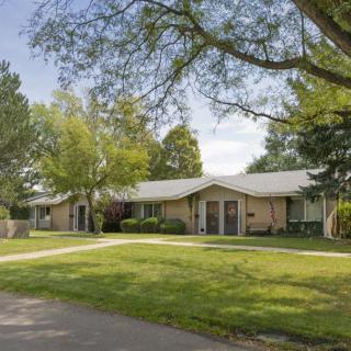 A suburban house surrounded by trees and a well-maintained lawn.