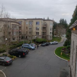 A view of an apartment complex with parked cars under an overcast sky.