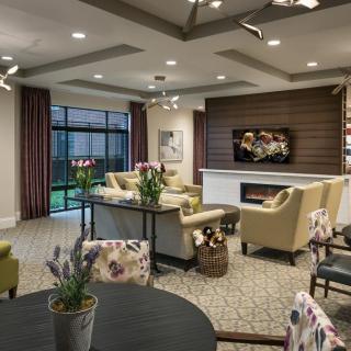 A modern living room with comfortable seating, a fireplace, and large windows overlooking the garden.