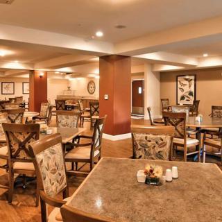 A warmly lit dining area with neatly arranged tables and chairs.