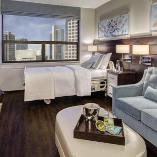 A modern hospital room with a city view, featuring a comfortable bed and luxurious amenities.