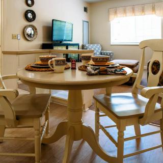 A cozy dining area with a round table set for breakfast, featuring chairs and a television in the background.