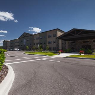 A modern building complex with a spacious parking lot on a sunny day.