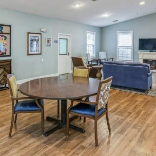 A spacious living room with wood flooring featuring a round table and chairs, a sofa set, and a fireplace.