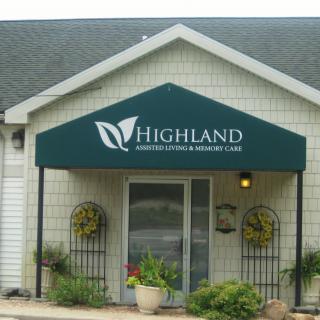 Entrance of Highland Funeral Home with plants and decorative awning.
