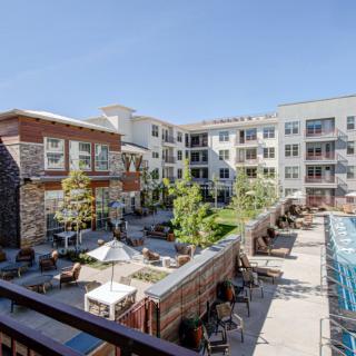 A modern apartment complex featuring a spacious courtyard with a pool and outdoor seating areas.