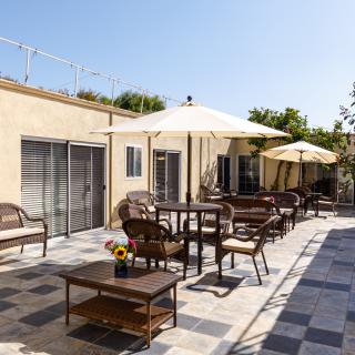 A sunny patio area with tables, chairs, and umbrellas for outdoor seating.
