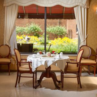 A beautifully set dining table awaits guests, offering a view of the vibrant garden outside.