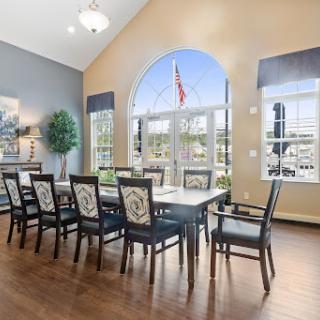 A spacious dining room featuring a large table and elegant chairs, bathed in natural light from the expansive windows.