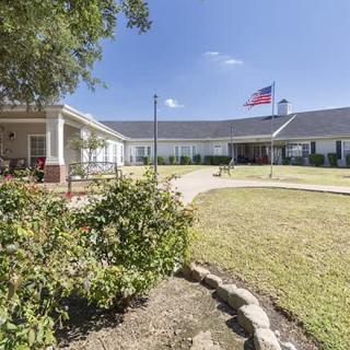A large house with a garden and an American flag flying in the front yard.